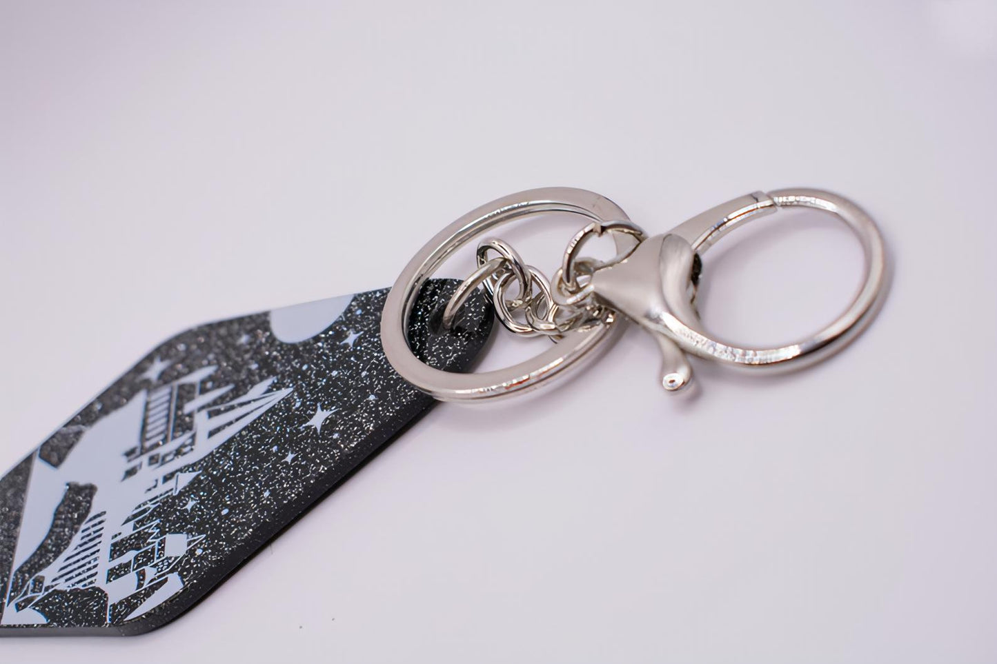 A close up of the accessory shows a lobster hook attached to a keyring which is attached to the keychain via silver chains.