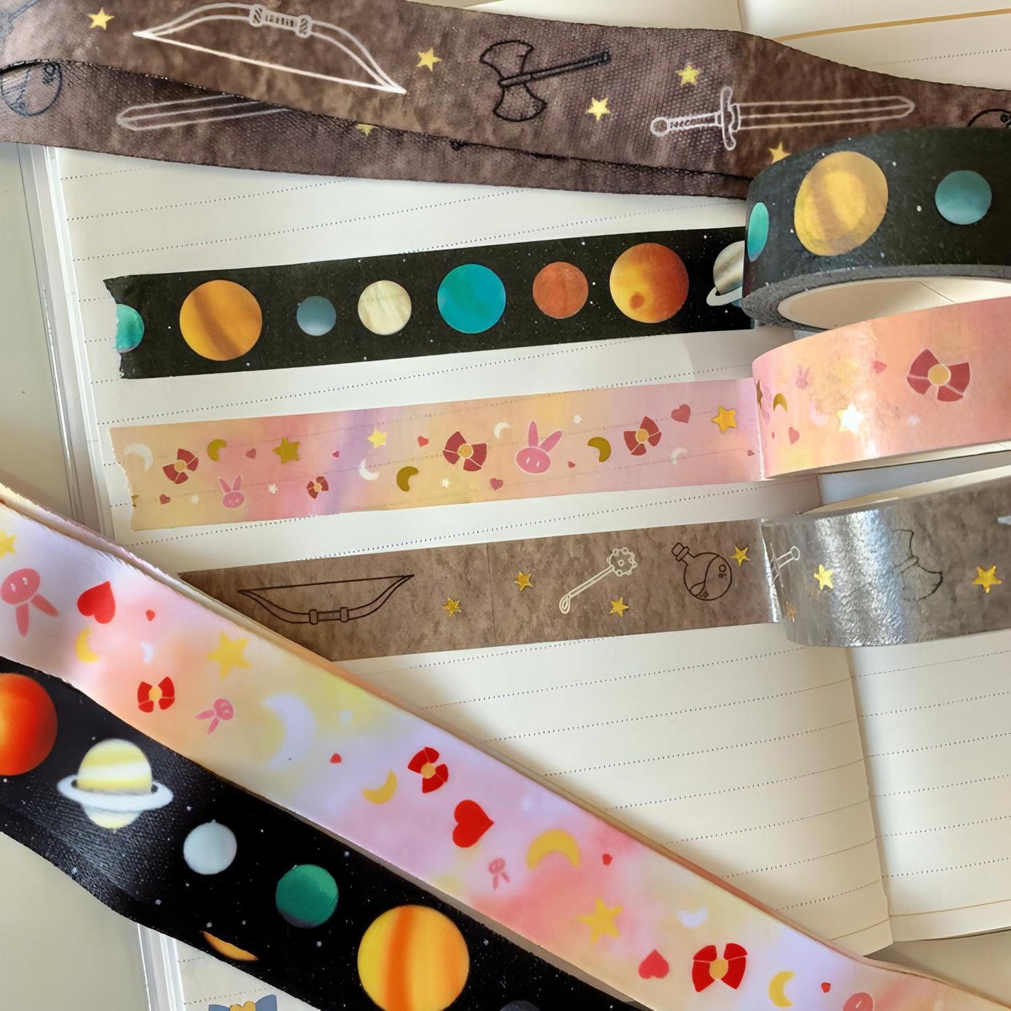Three washi tape designs are in the centre. Top to bottom they are galactic, anime, and fantasy. At the top of the image is a fantasy lanyard. At the bottom are the galactic and anime lanyards.