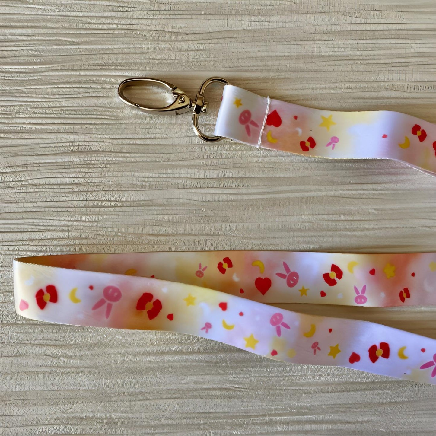 THe image shows the lanyard from a top-down angle. This shows the pattern more clearly; each symbol is small (around 2mm wide) and they are interspersed with each other up and down the lanyard. The image also shows the metal oval hook at the end.