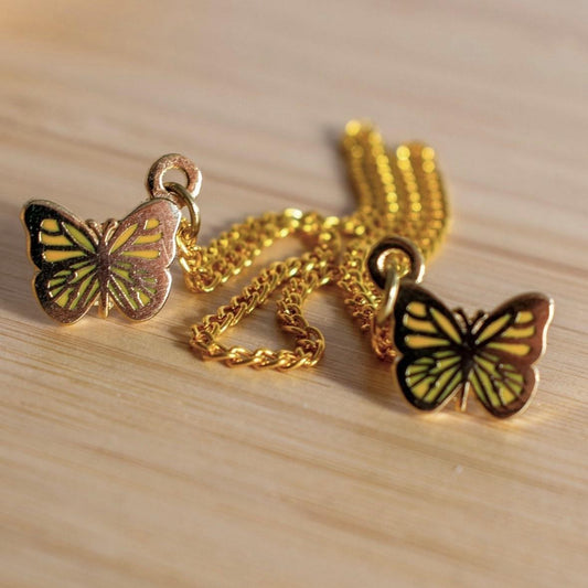 Very small butterflies in orange enamel and gold metal are joined by two gold chains of 10cm and 15cm each.
